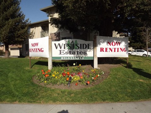 three signs in the grass in front of a building
