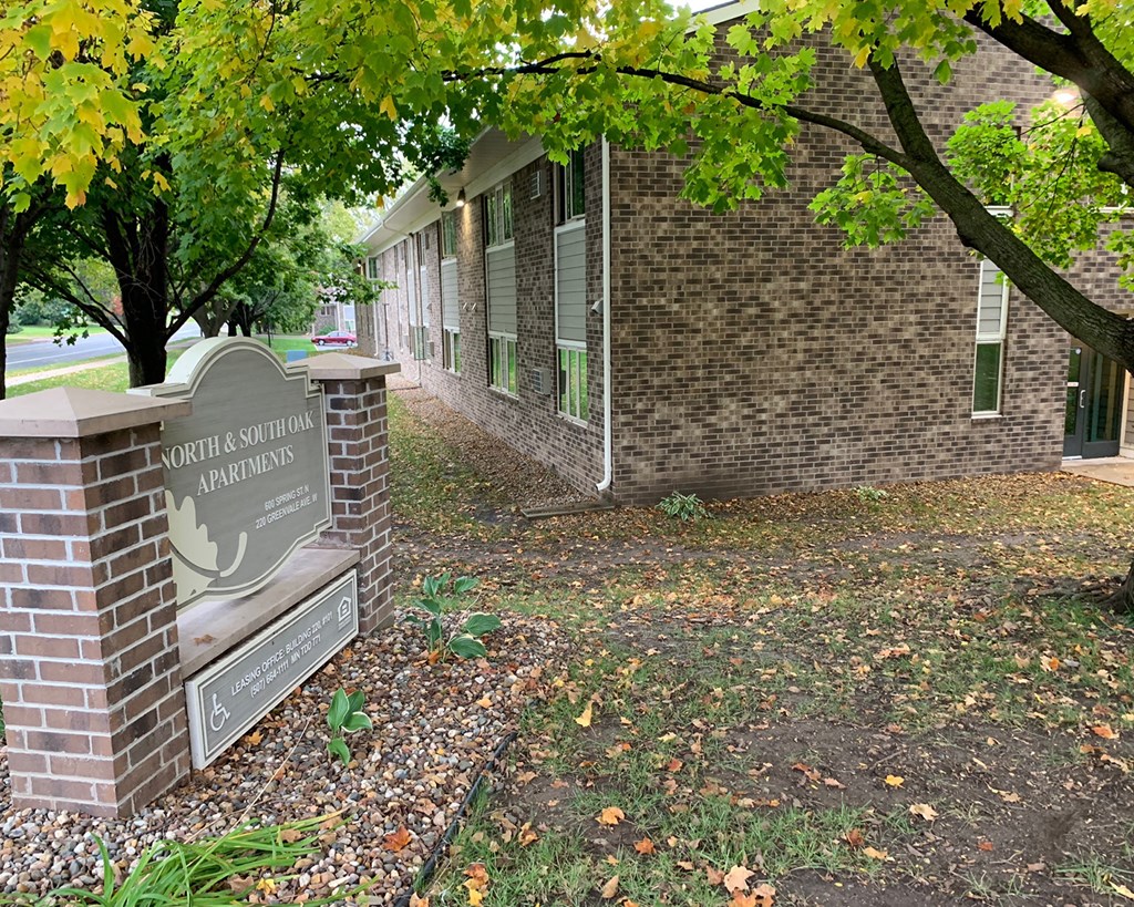 a brick building with a sign in front of a tree