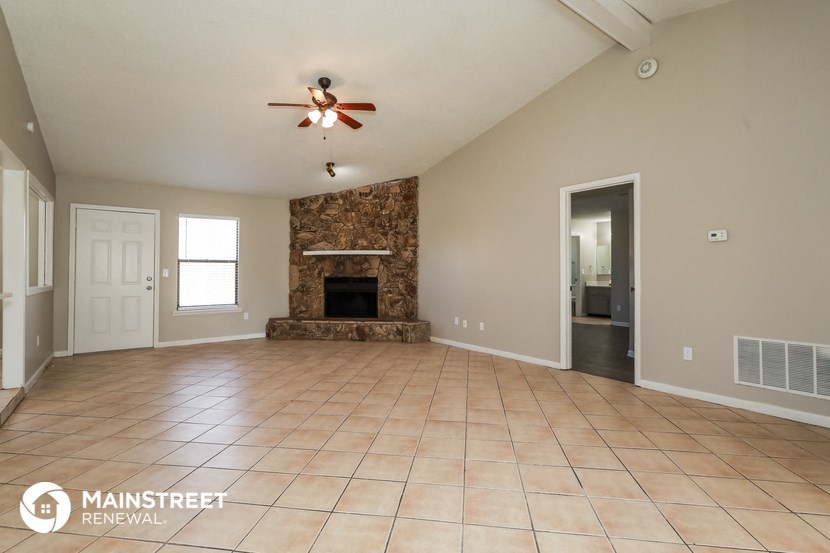 an empty living room with a fireplace and a ceiling fan