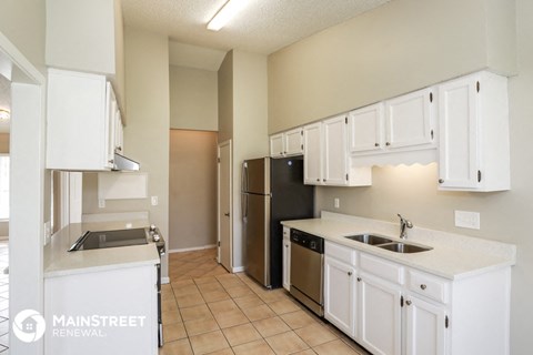 a kitchen with white cabinets and a stainless steel refrigerator