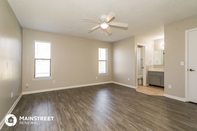 an empty living room with wood flooring and a ceiling fan