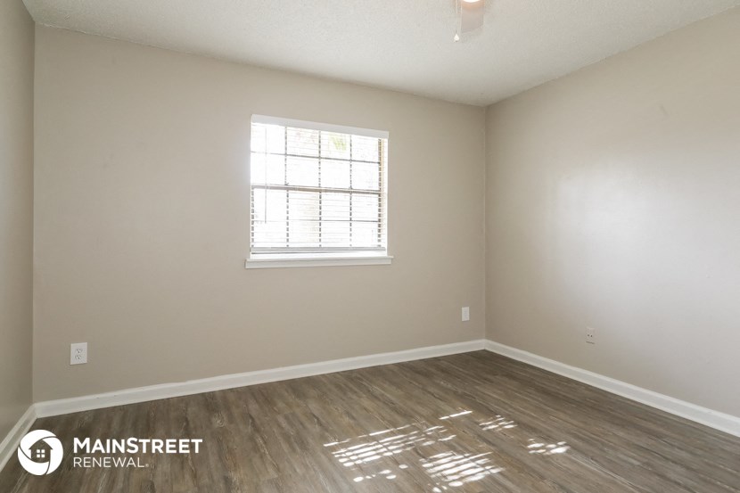 the living room of an empty apartment with wood flooring and a window