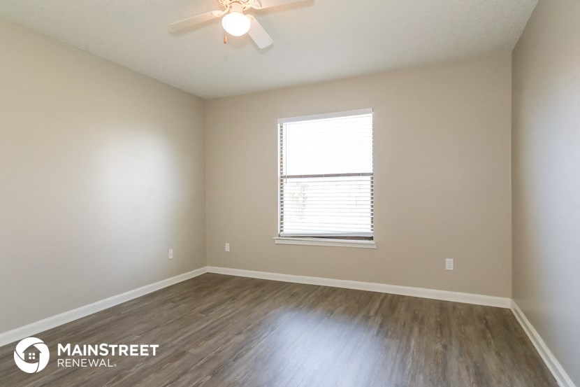 the spacious living room with wood floors and a ceiling fan