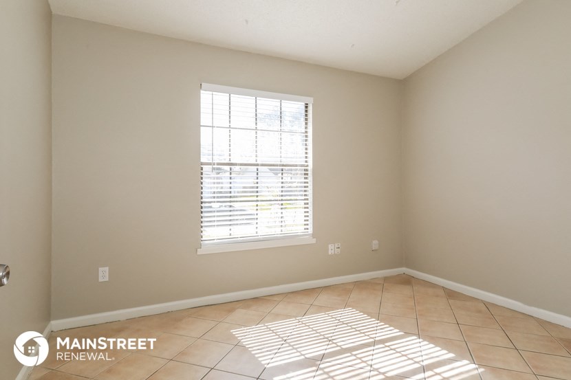 the living room of a home with tiled floors and a window