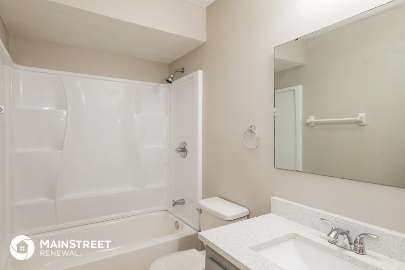 a white bathroom with a tub and a sink and a mirror