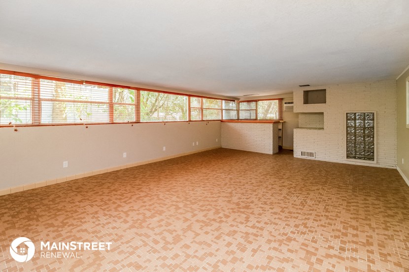 an empty living room with a large window and a brick floor
