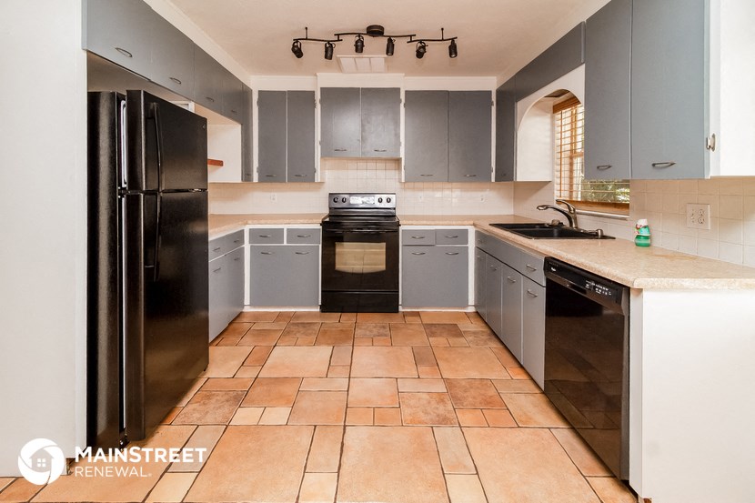 a large kitchen with a black refrigerator and a sink