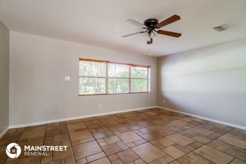 the living room has a ceiling fan and a large window