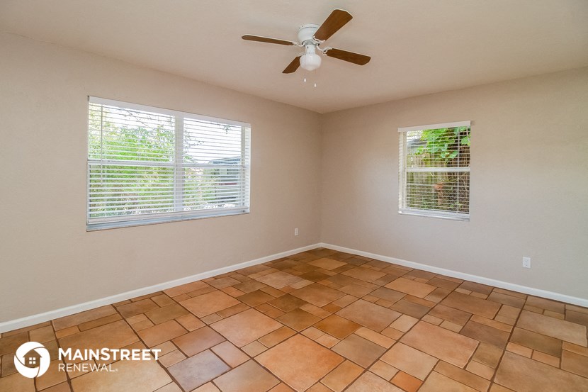 an empty room with a ceiling fan and two windows