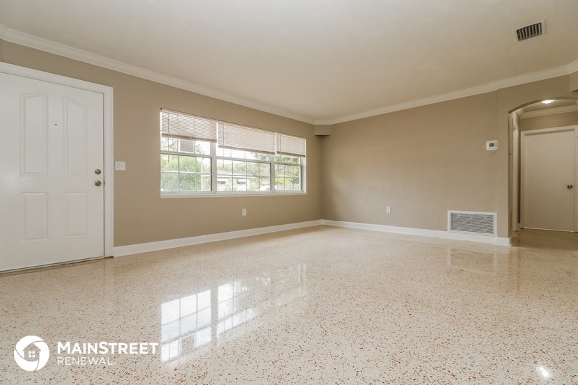an empty living room with a white door and a window