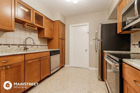 a kitchen with wooden cabinets and stainless steel appliances and a black refrigerator