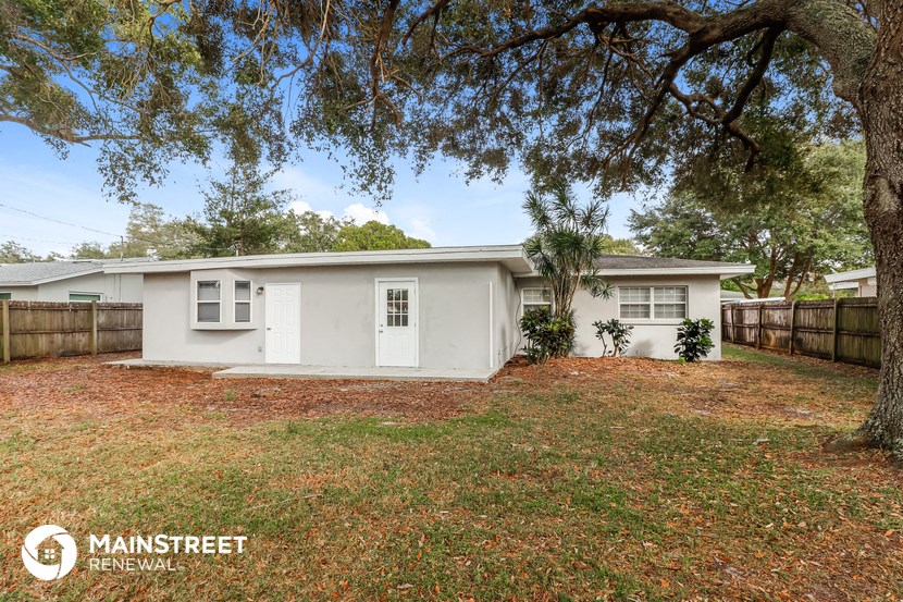 a small white house with a yard and a tree