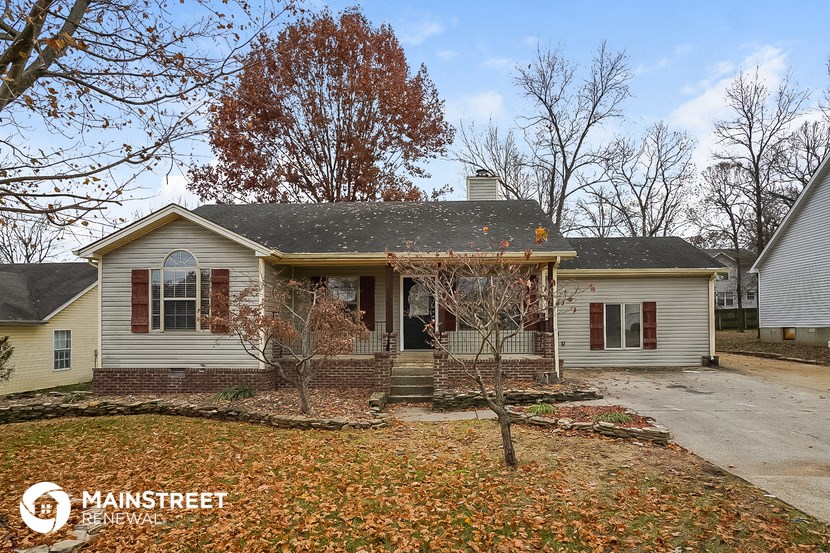 the front of a white house with a yard and trees