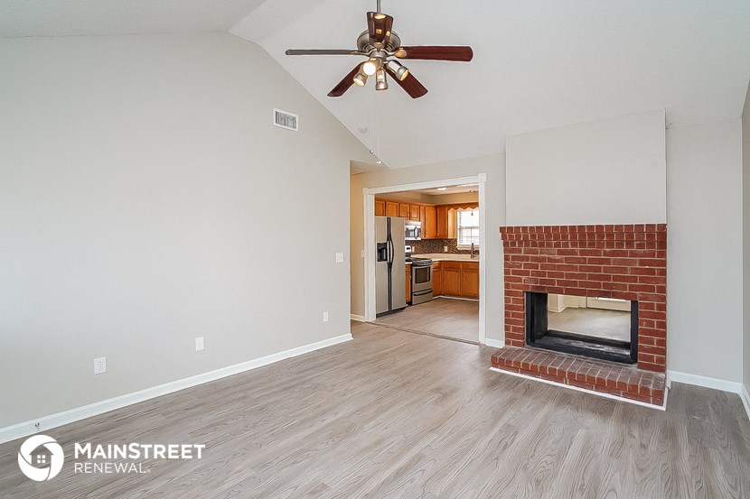 a living room with a brick fireplace and a ceiling fan
