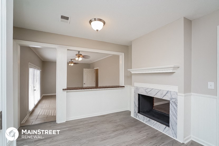 a living room with a fireplace and a hallway