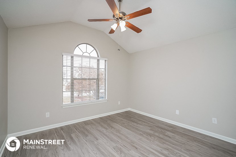 the spacious living room has a ceiling fan and a large window