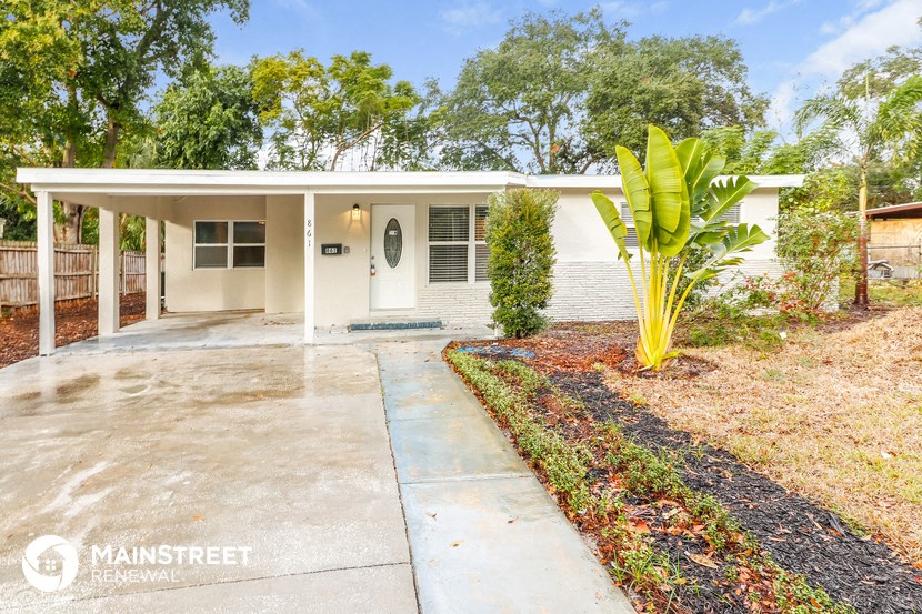 a white house with a concrete driveway and a palm tree