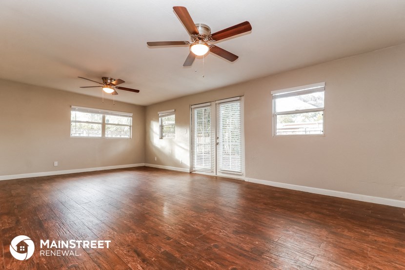 the living room of a home with wood floors and a ceiling fan