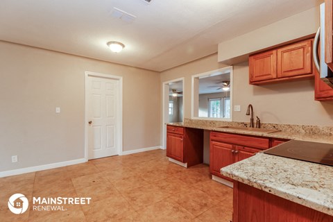 a kitchen with wooden cabinets and granite counter tops and a sink and a door