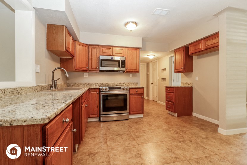 a kitchen with wooden cabinets and granite counter tops and a sink and stove
