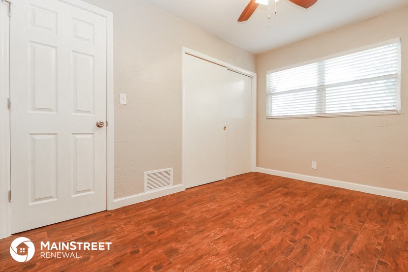 the living room of a home with wood flooring and a white door