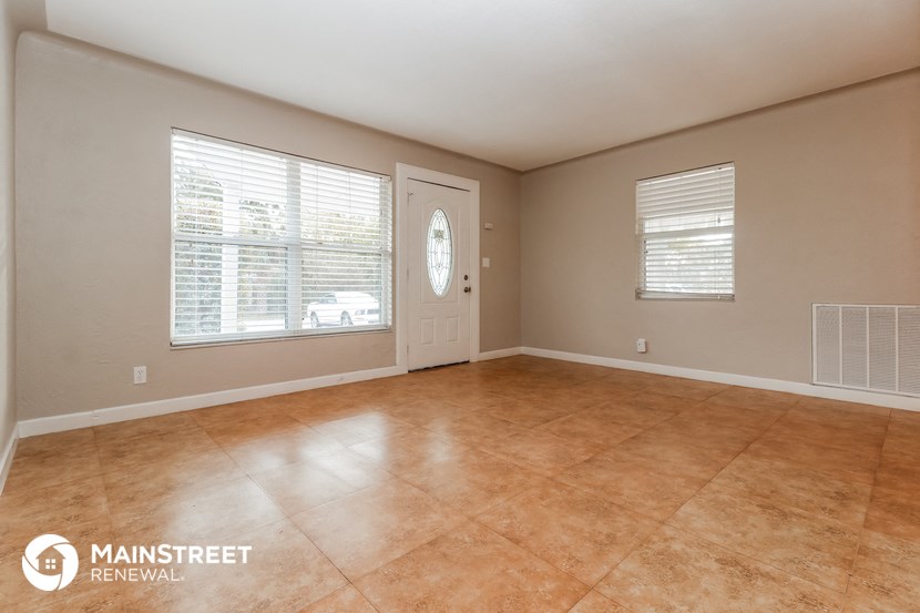 the living room of a home with tile floors and a white door