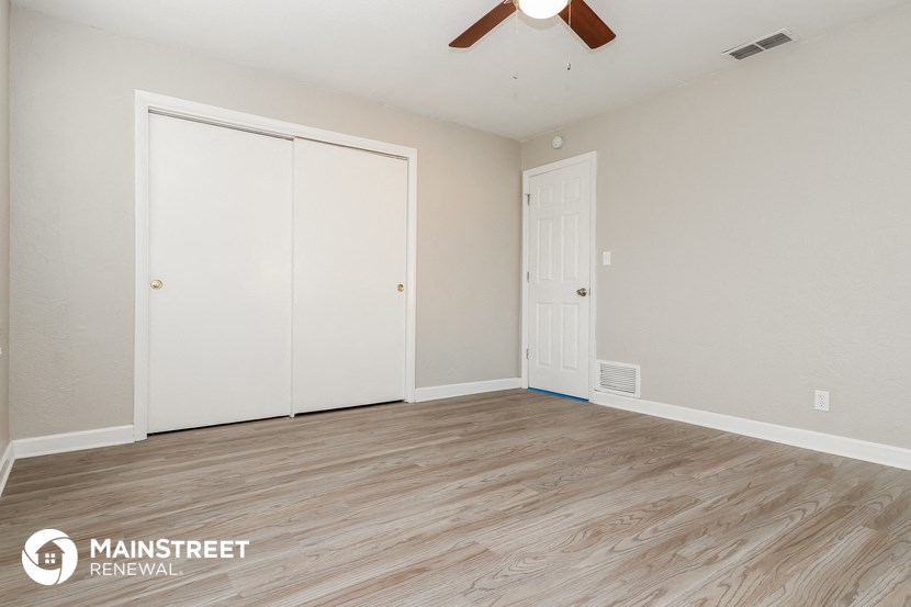 the spacious living room with two closets and a ceiling fan