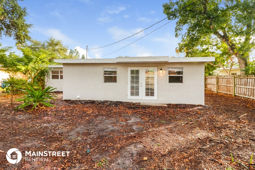 a small white house with a yard and trees