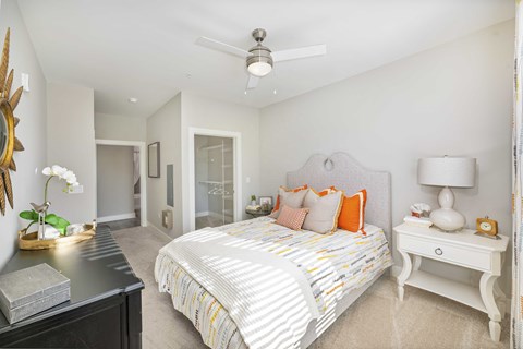 A bedroom with a bed, nightstand, and a ceiling fan.