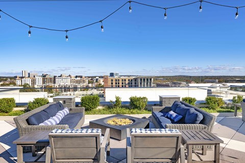 A rooftop patio with furniture and string lights.