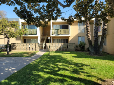 the exterior of an apartment building with a sidewalk and grass