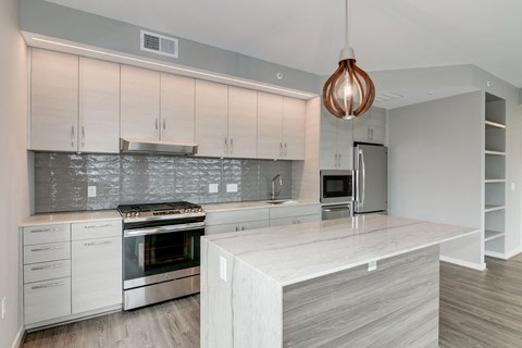 A modern kitchen with a stainless steel refrigerator and a copper pendant light.