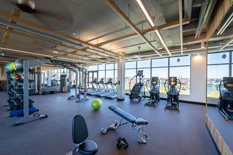 A gym with a variety of equipment including weights and cardio machines.