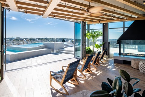 A sunny day at the poolside with chairs and plants.
