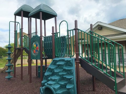 A playground with a green slide and a green roofed structure.