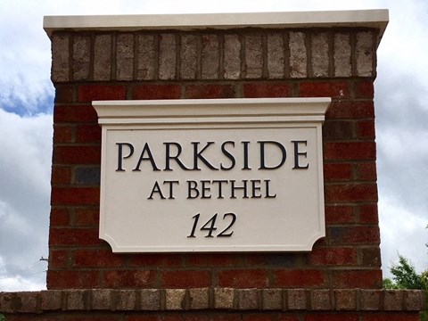 A sign that says "Parkside at Bethel 142" is mounted on a brick wall.