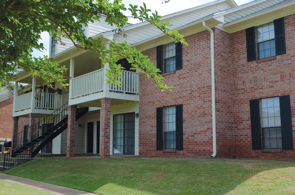 A red brick building with a white roof and a balcony.