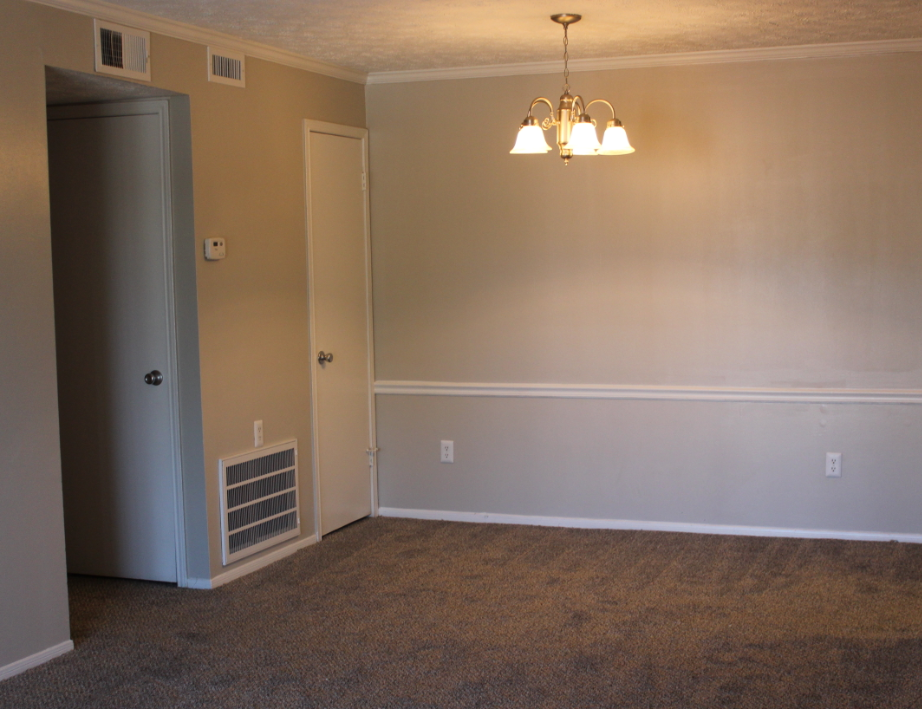 A room with a carpeted floor and a chandelier hanging from the ceiling.