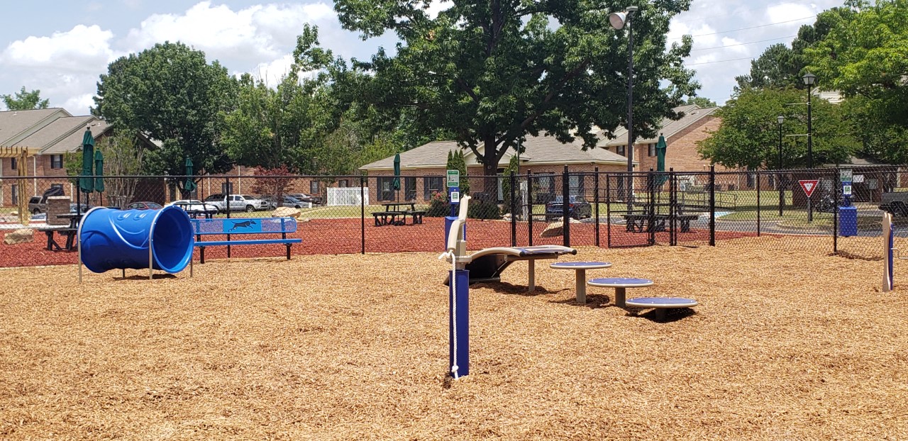 A playground with a blue slide and a red flag.