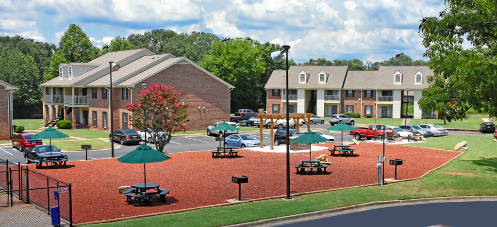 A playground with a red surface and green umbrellas.