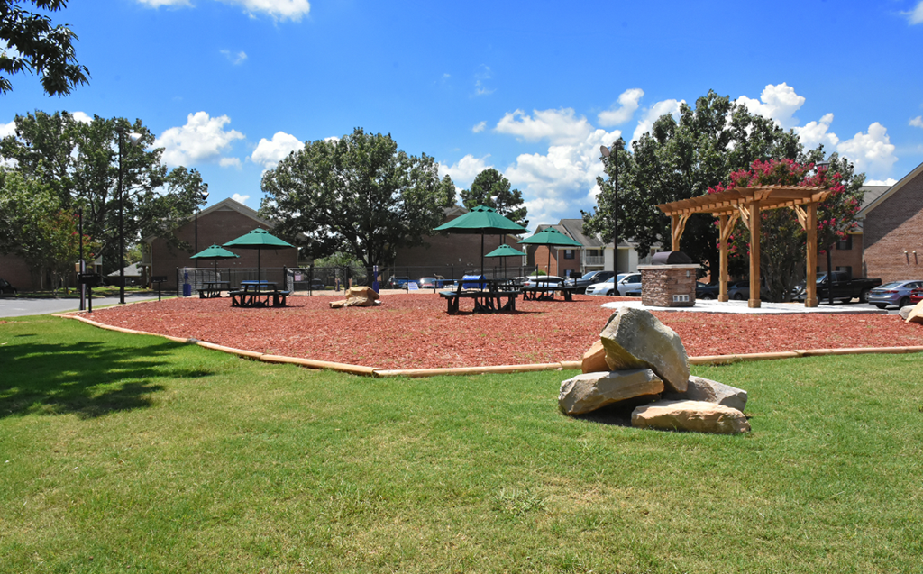 A park with a pile of rocks in the middle of a grassy area.