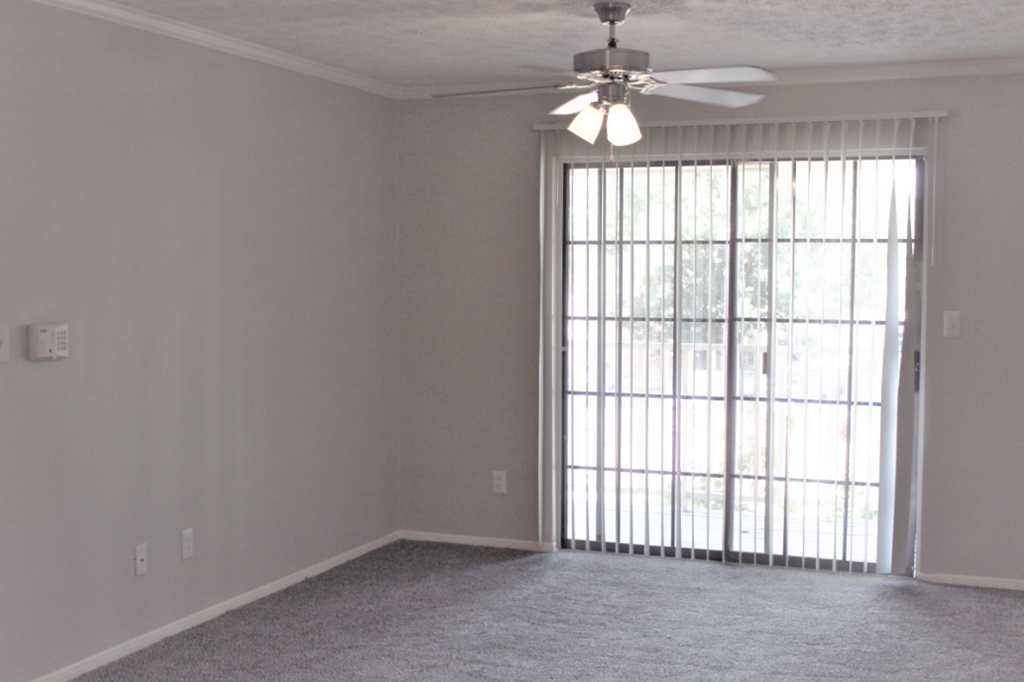A room with a ceiling fan and a window with blinds.