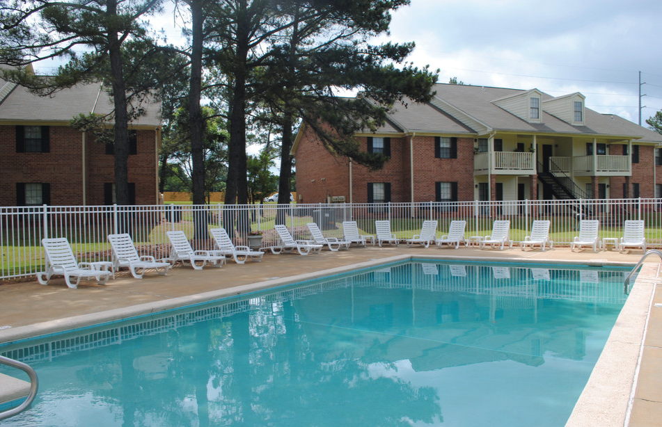 A pool with chairs around it and a building in the background.