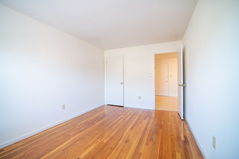 an empty living room with wood floors and white walls