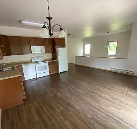 A kitchen with wooden floors and white appliances.