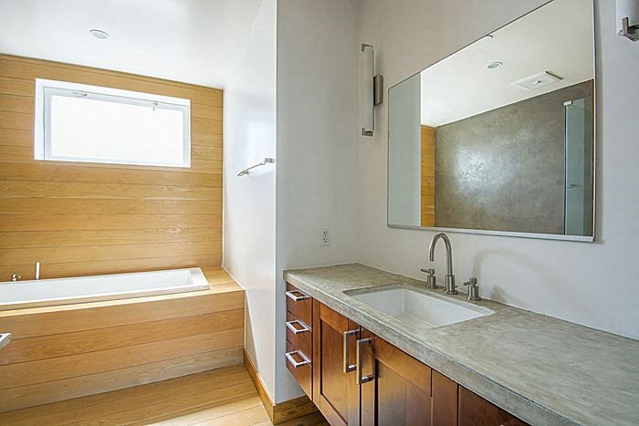 A bathroom with a tub, sink and mirror.