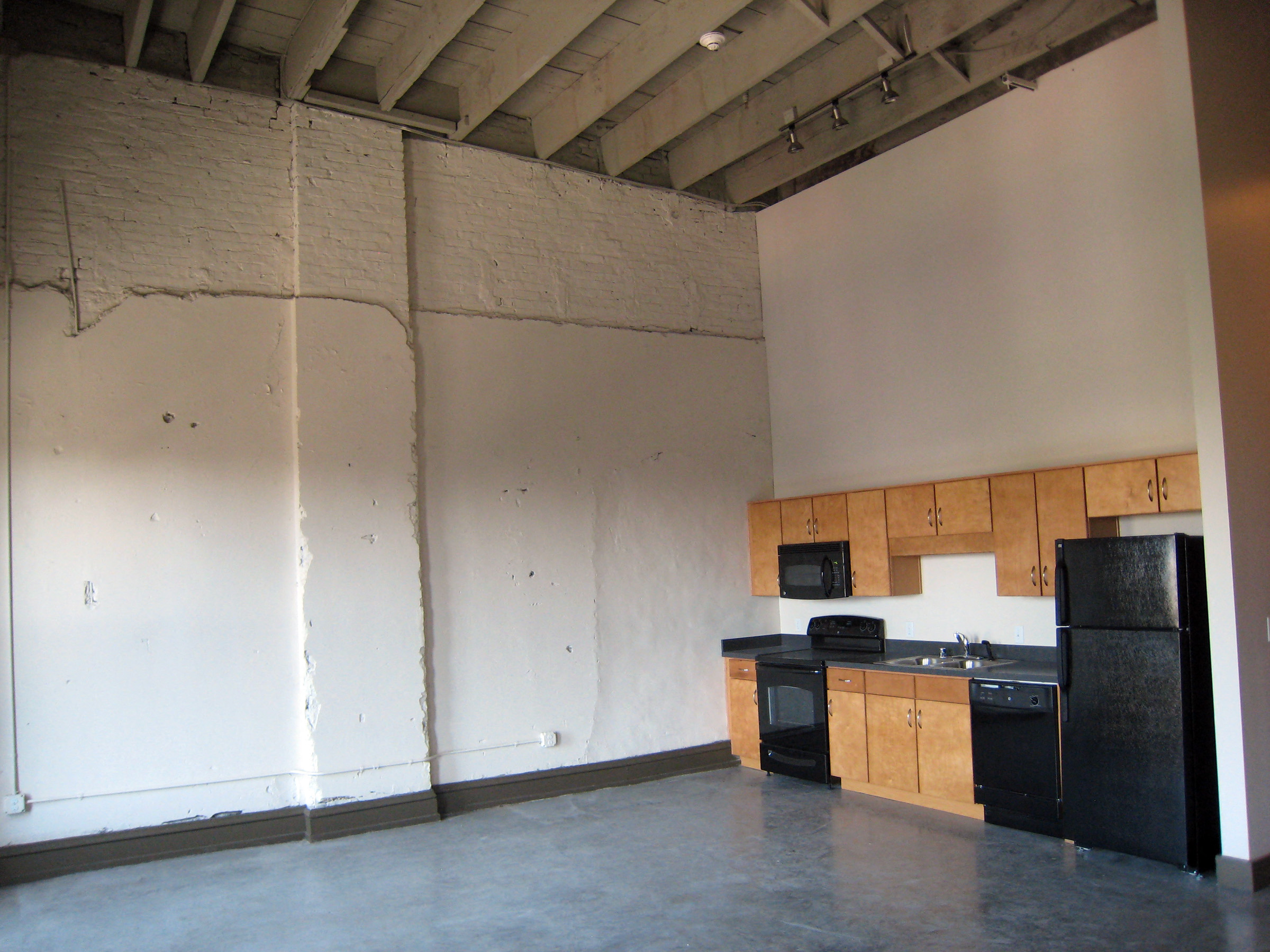 an empty kitchen with white walls and black appliances