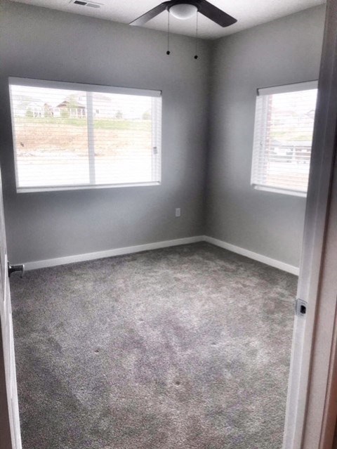 an empty room with a carpeted floor and two windows