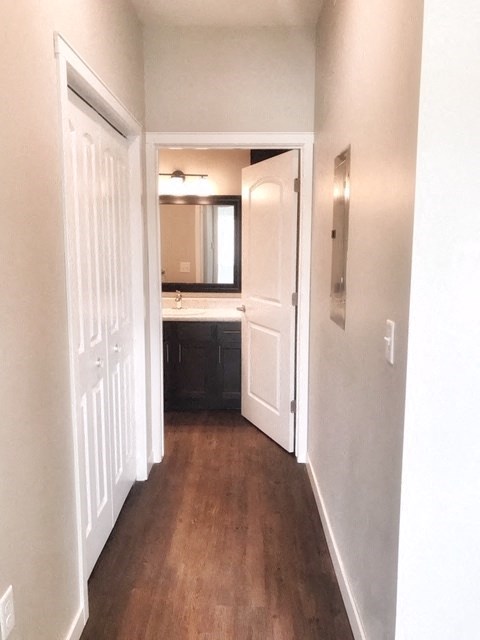 a hallway with a door to a bathroom and a sink