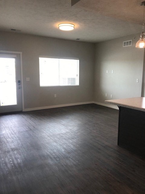an empty living room with wood floors and a window